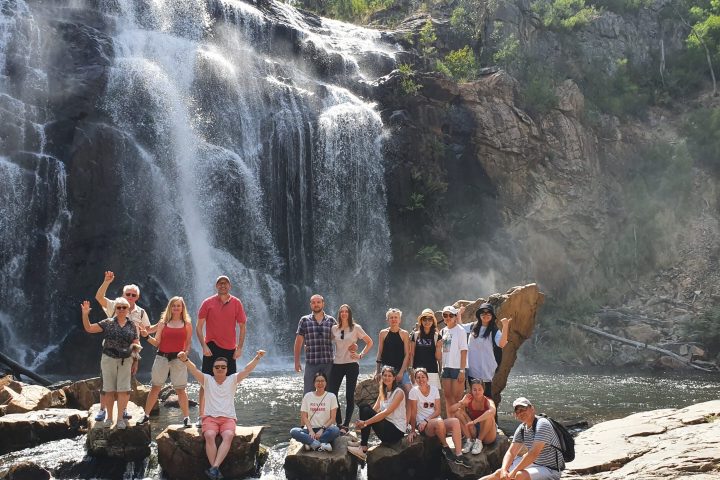 a group of people standing next to a waterfall